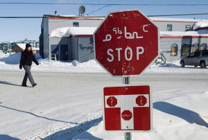 A person walks past a stop sign displayed in both English and Inuktitut in the city of Iqaluit, Nunavut