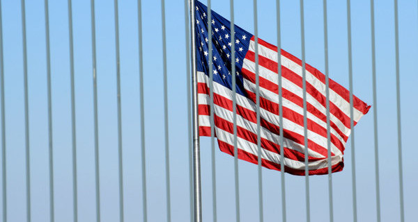 American flag flies behind a tall fence surrounding the United States Consulate General building in Jerusalem, Israel.